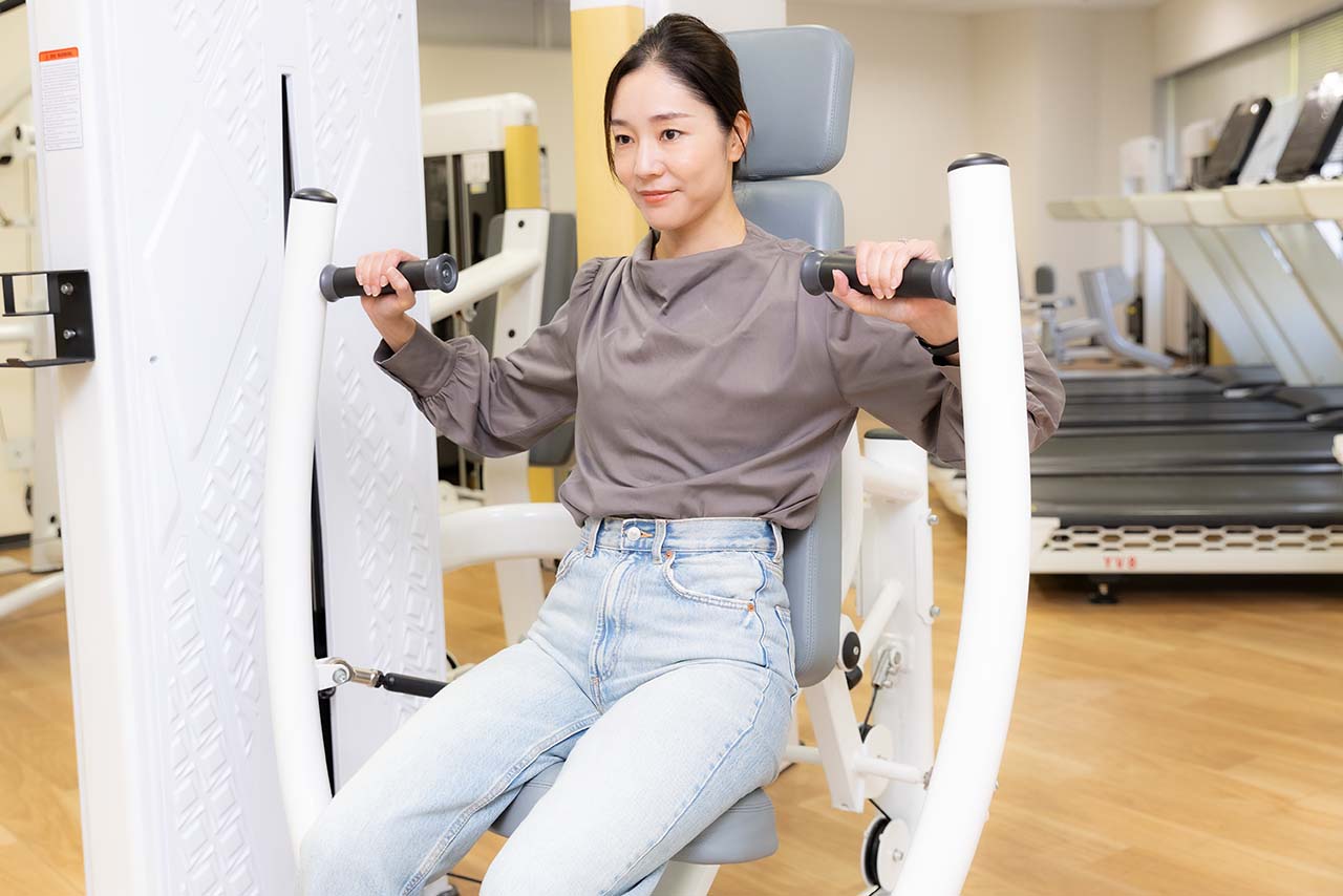 チェストプレスのマシンでトレーニングする千春さん。肘が下がらないように注意しながらレバーを動かす