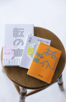 『母影』を出版する際も、尾崎はかつて働いていた製本会社を指定。17年ぶりに訪問し、当時の上司に教わりながら、作業服姿で本のカバーを巻く動画を公開