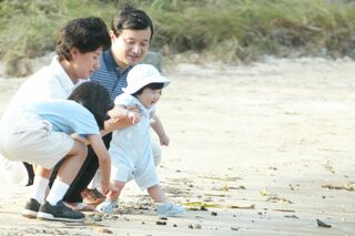 初めて訪れた須崎御用邸内の三井浜で遊ばれる生後8か月の愛子さま。雅子さまに支えられながらニコニコ笑顔で浜辺デビュー　写真／JMPA、『週刊女性』写真班