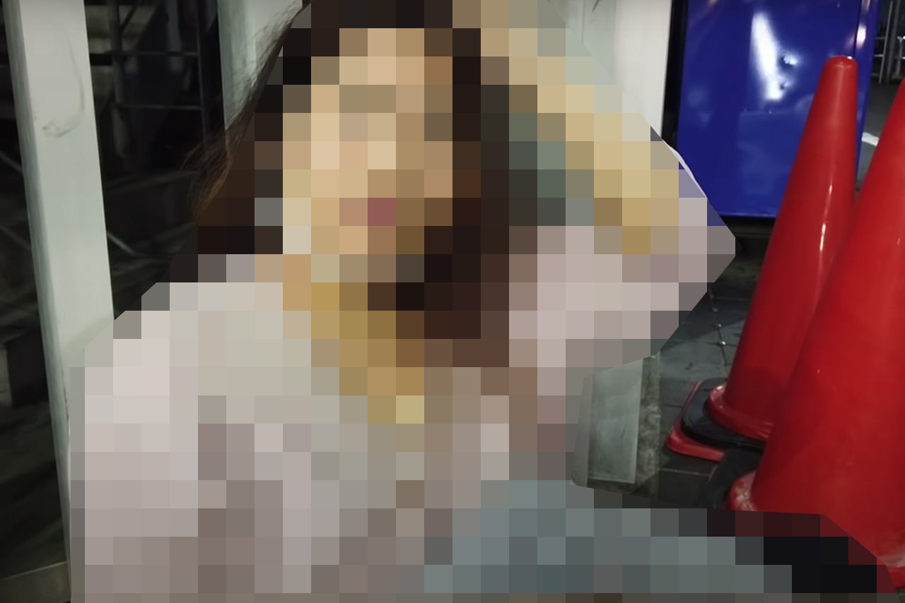 路上に座り込んでインタビューに答える女性（YouTubeより）