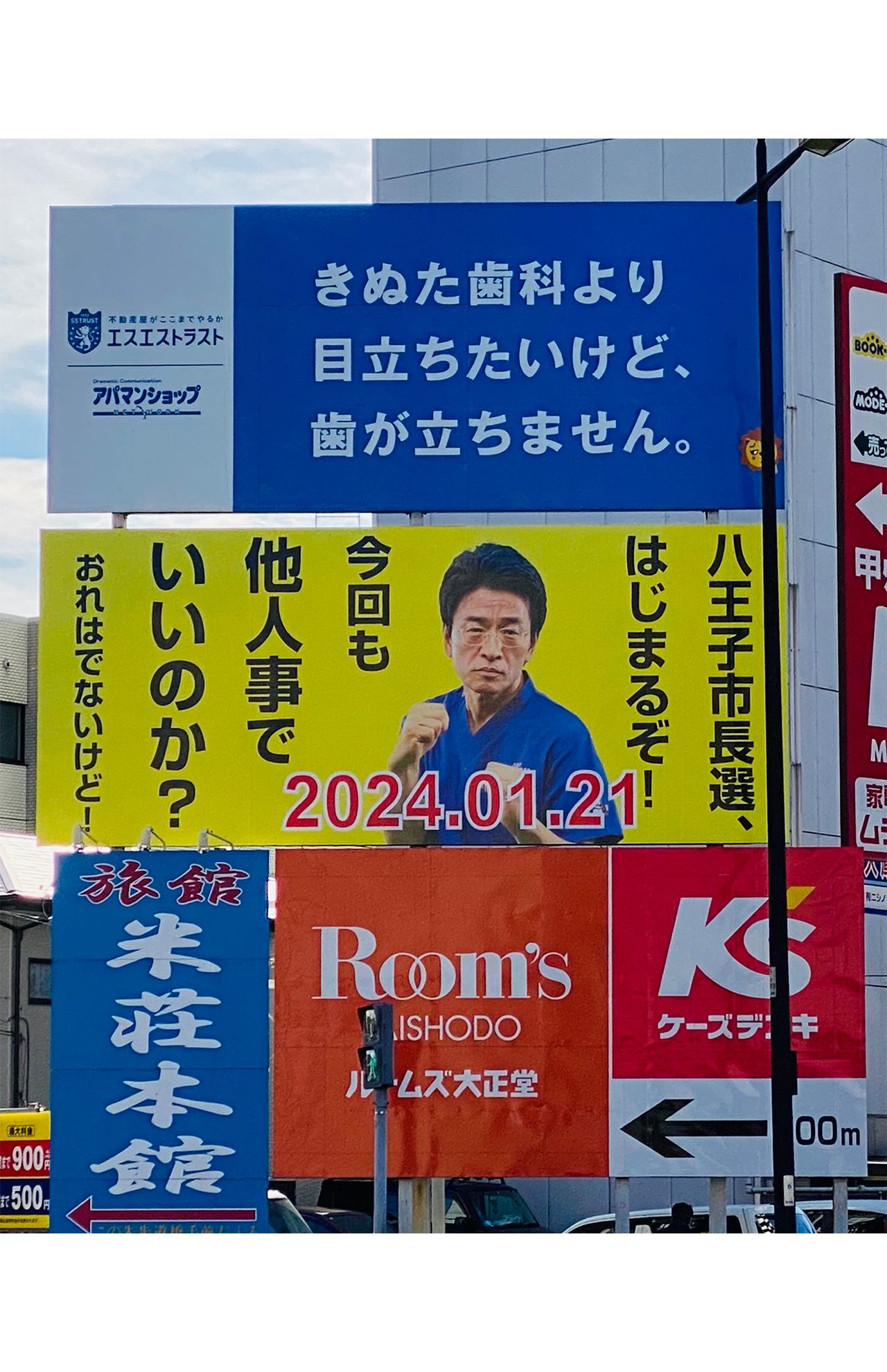 '24年1月に掲げられたきぬた歯科のある八王子の市長選投票を呼びかける看板。上の某不動産会社の看板も“きぬた”を意識したものに……