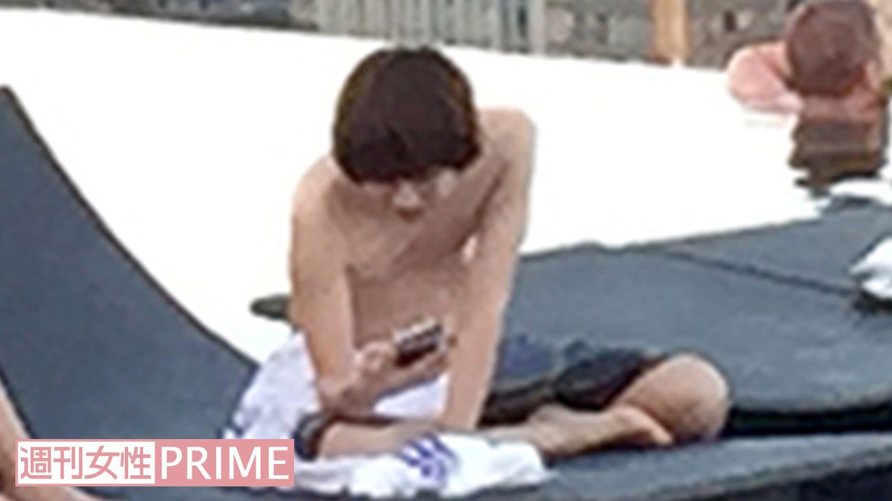 シンガポールのプールサイドで携帯電話を操作する伊野尾