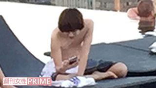 シンガポールのプールサイドで携帯電話を操作する伊野尾