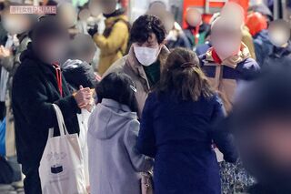 女性2人組にカイロを手渡した後、目を合わせて会話をする鈴木亮平