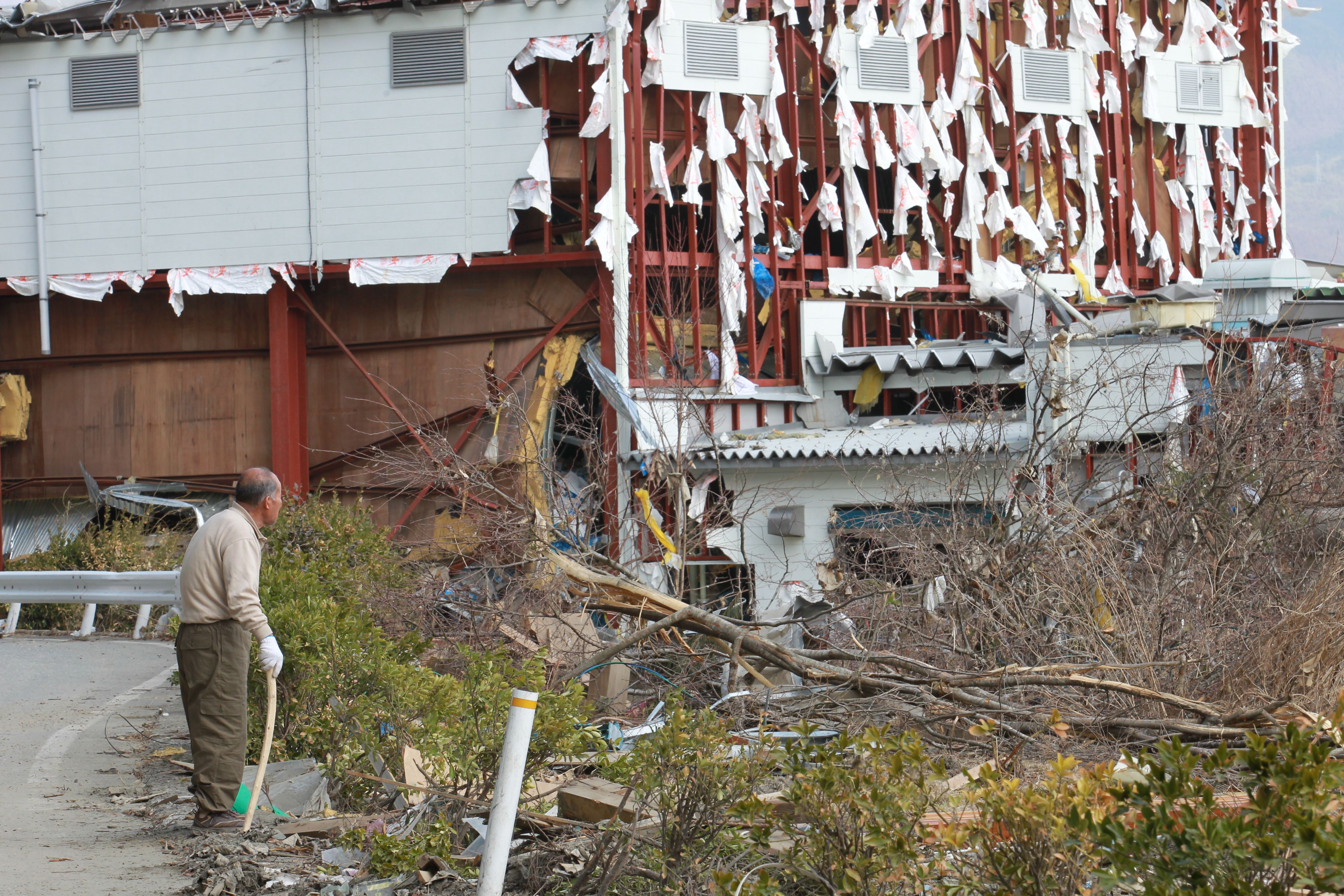 工場だろうか、ボロボロになった建物を見つめる住民（陸前高田市、2011年3月29日〜4月1日）