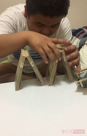 札束でピラミッドタワーを作って遊んでいる西容疑者（読者提供）