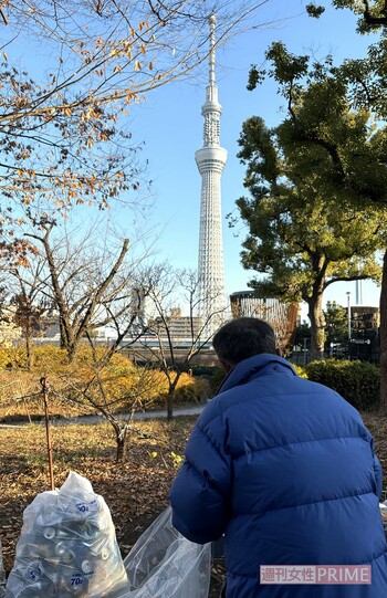 空き缶を袋に詰めながらスカイツリーを見上げる板倉さん（仮名）　撮影／編集部