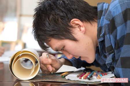 作品に顔を近づけ色鉛筆で細かく色づけをしていく憲満さん。「軍歌」などテンポのいい音楽を流しながら描くことも　撮影／伊藤和幸