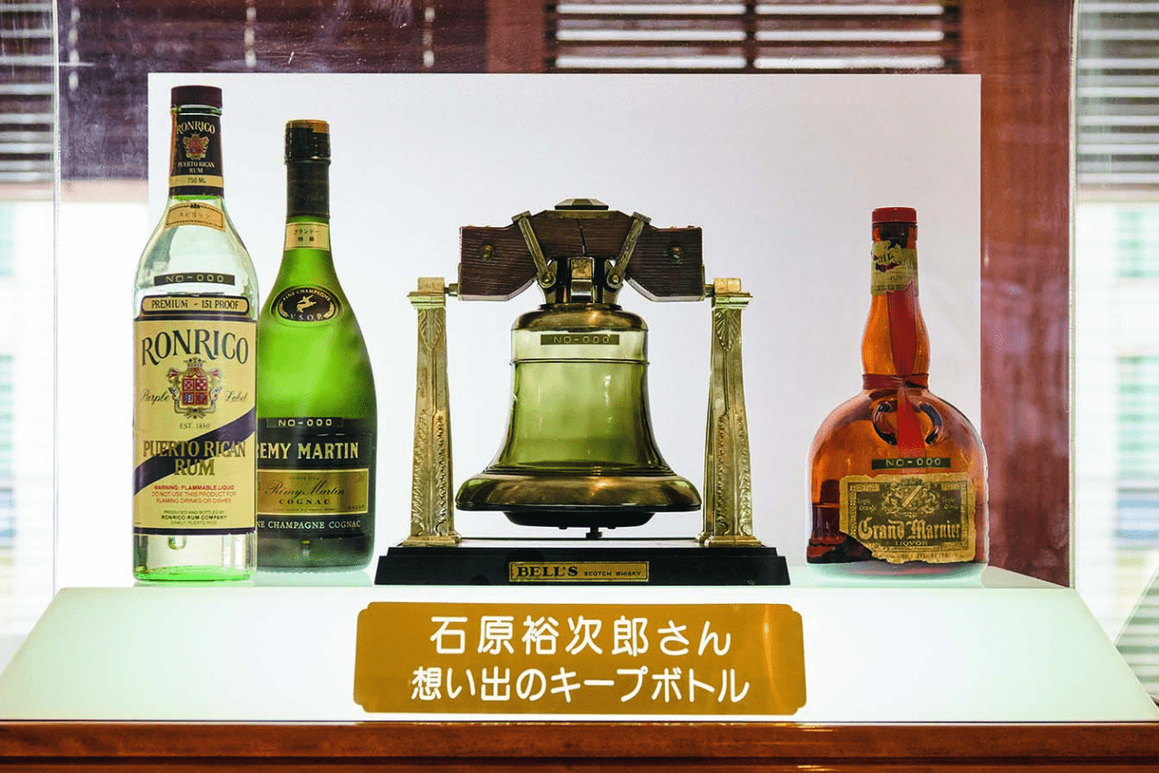 裕次郎さん思い出のキープボトル。左からロンリコ（ラム酒）、レミーマルタン（ブランデー）、デキャンタに入ったベル（ウイスキー）、グラン・マルニエ（オレンジ・リキュール）