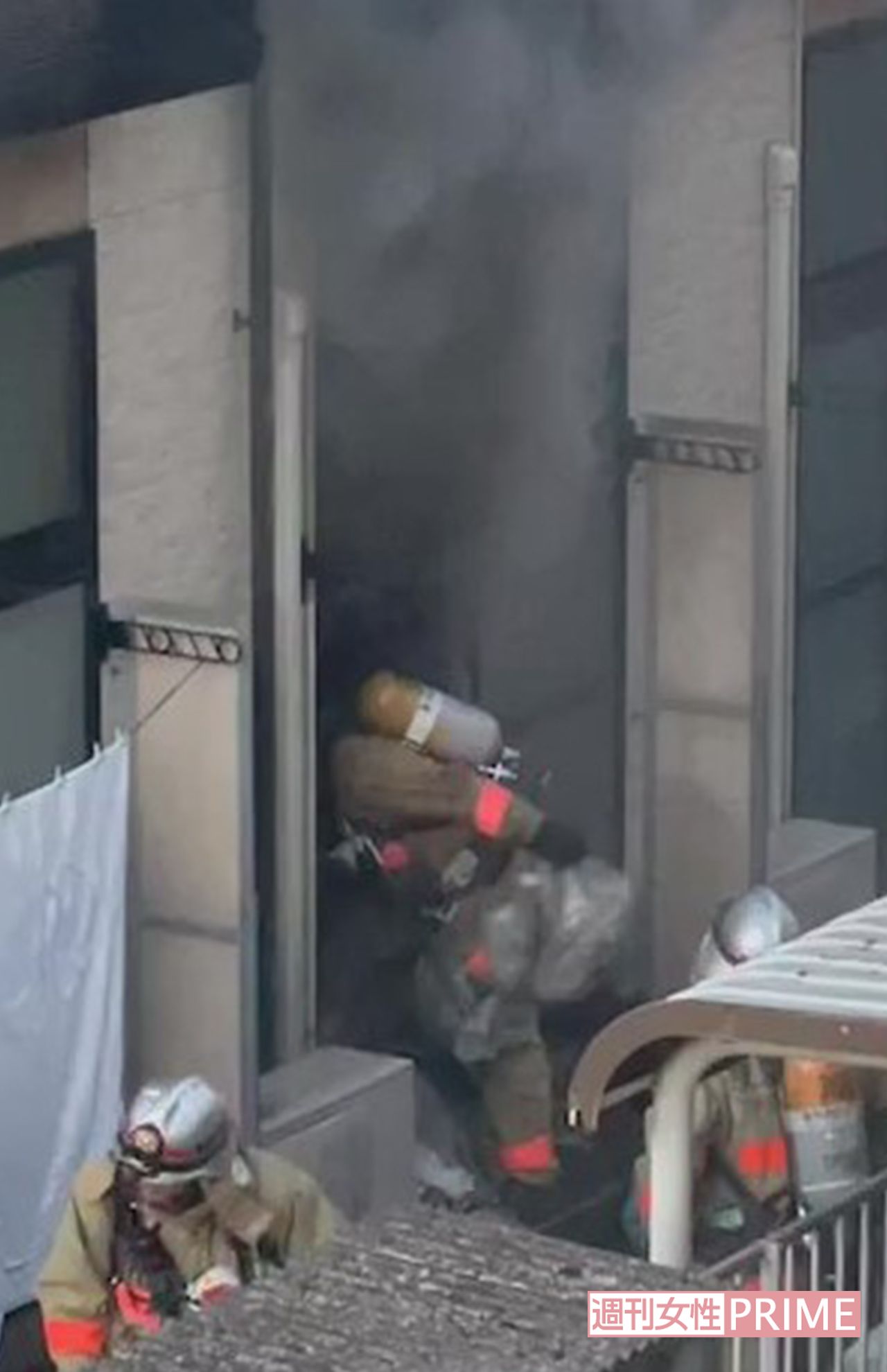 火の手がおさまると、消防隊員は田原春貴之容疑者の部屋に残ったゴミ袋を次々と屋外に放り投げた（目撃者提供）