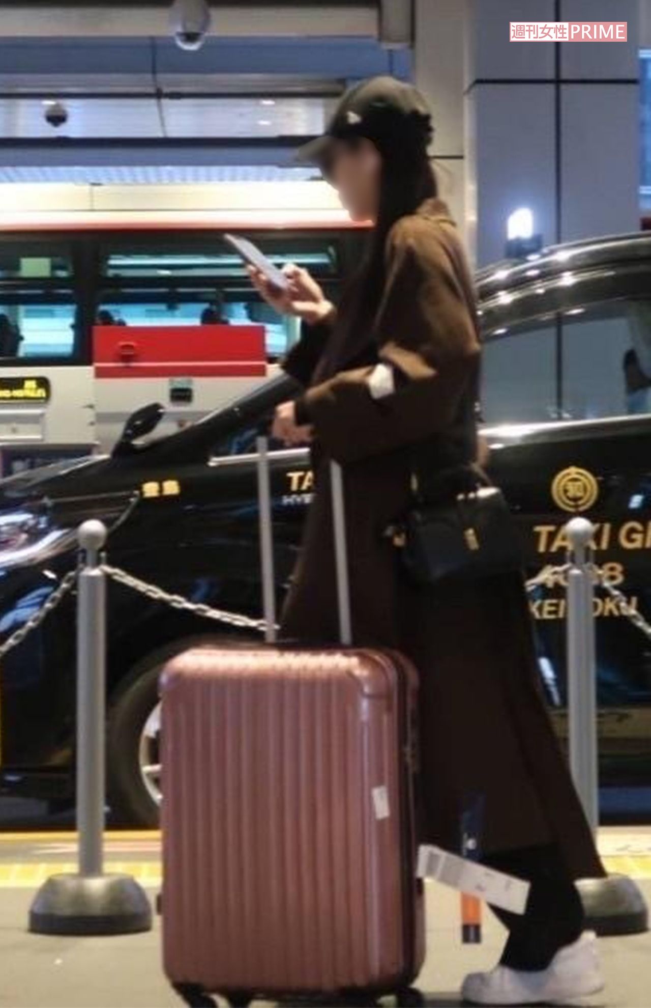 足早にピンクのスーツケースを運ぶ女性