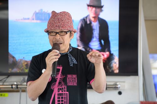 ツアーのオリジナルＴシャツや缶バッジを身に着け、ガイドを行う黒沢さん