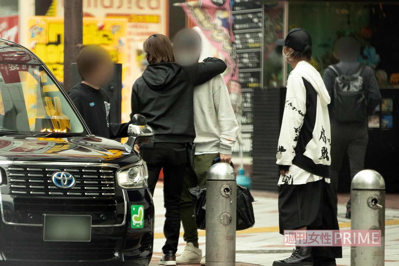 タクシーに乗り込む前、共に一夜を過ごした男性をだきしめる堂本光一（左）と見守る上田竜也（右）