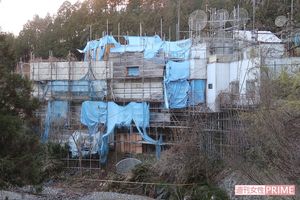足場が組まれ、シートに覆われた改築中の小川さんの自宅。屋上にはいくつものアンテナが