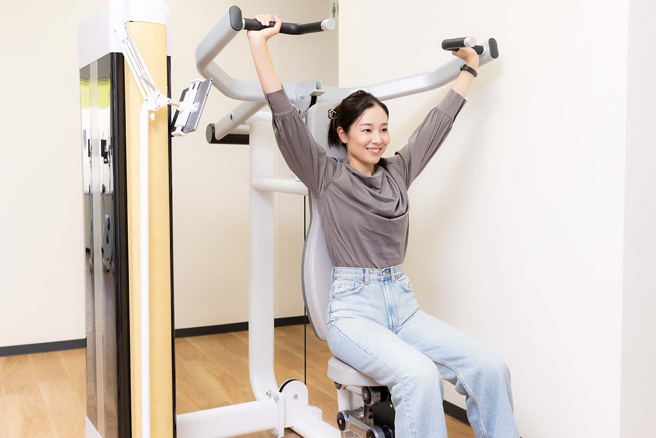 ショルダープレスのマシンでトレーニングする千春さん。レバーを上げ下げするときは、肘が手首の真下にくるように意識するのがコツ