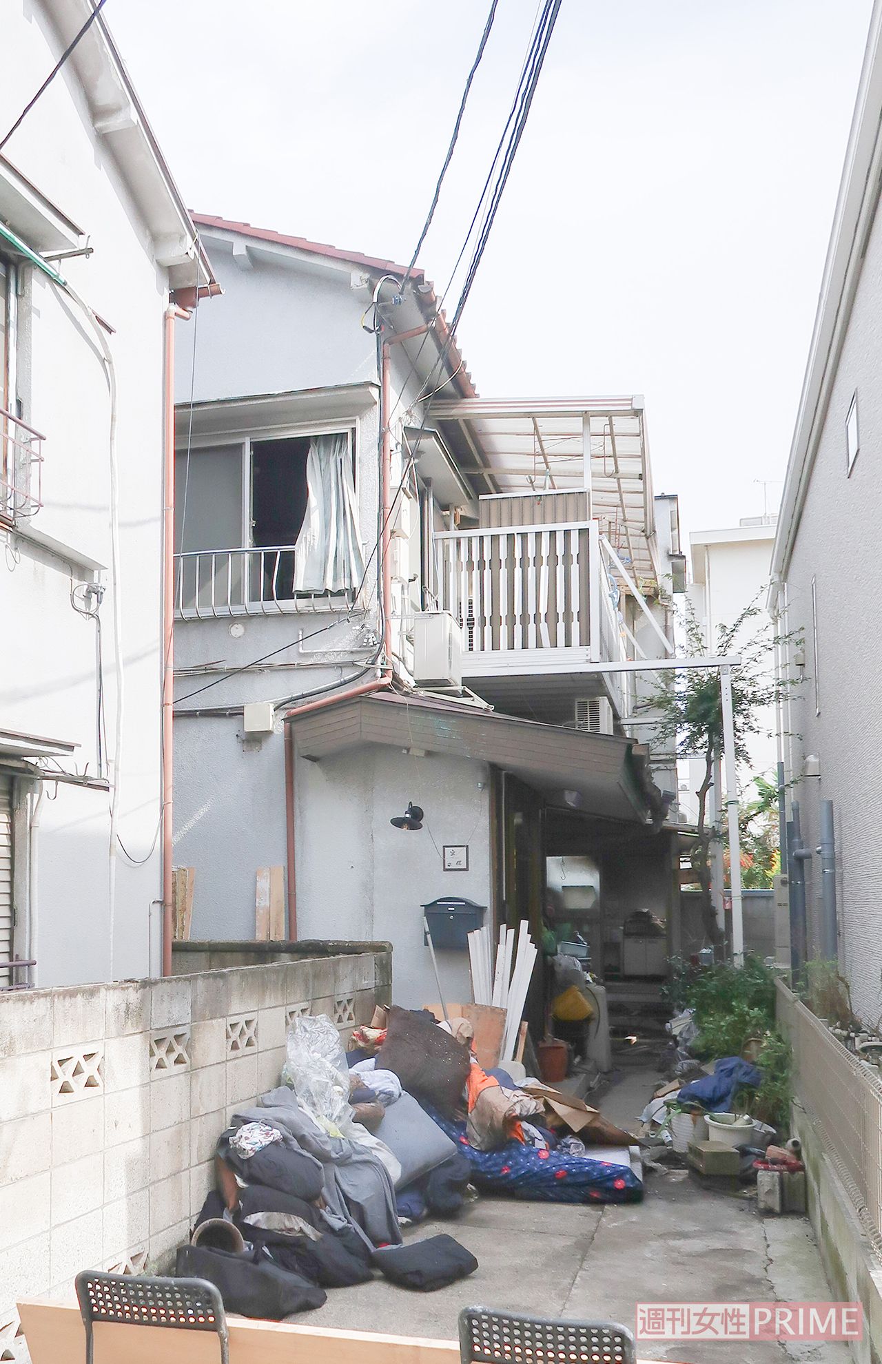 放火されたアパート（奥）。窓は開け放たれ、家財道具は外に出された