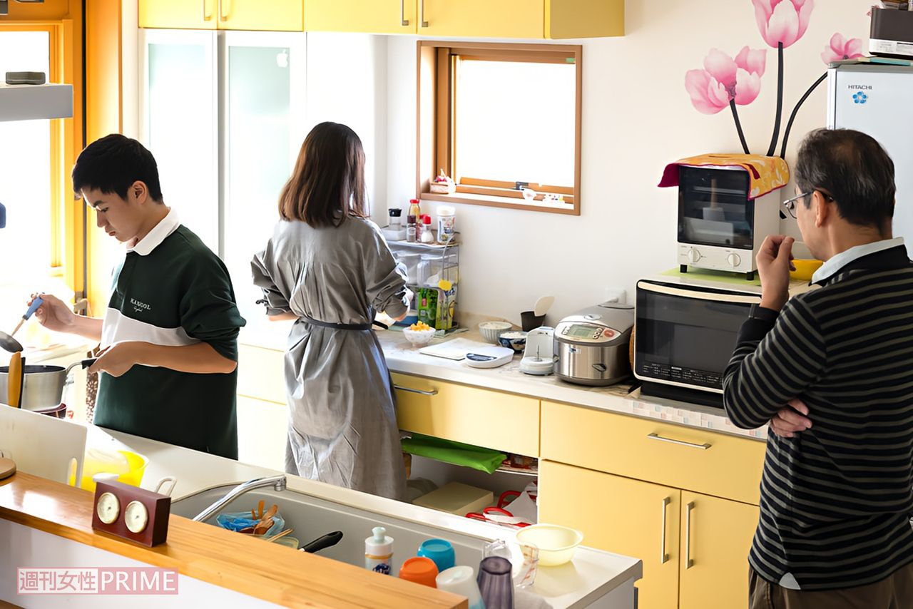  伊鈴さんが遺してくれたレシピノートを見ながらキッチンで母の味を再現する優華さんと健渡くん、それを見守る父・浩徳さん写真／『家族のレシピ』（幻冬舎）より