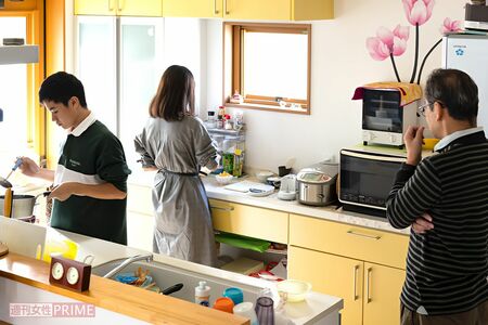  伊鈴さんが遺してくれたレシピノートを見ながらキッチンで母の味を再現する優華さんと健渡くん、それを見守る父・浩徳さん写真／『家族のレシピ』（幻冬舎）より