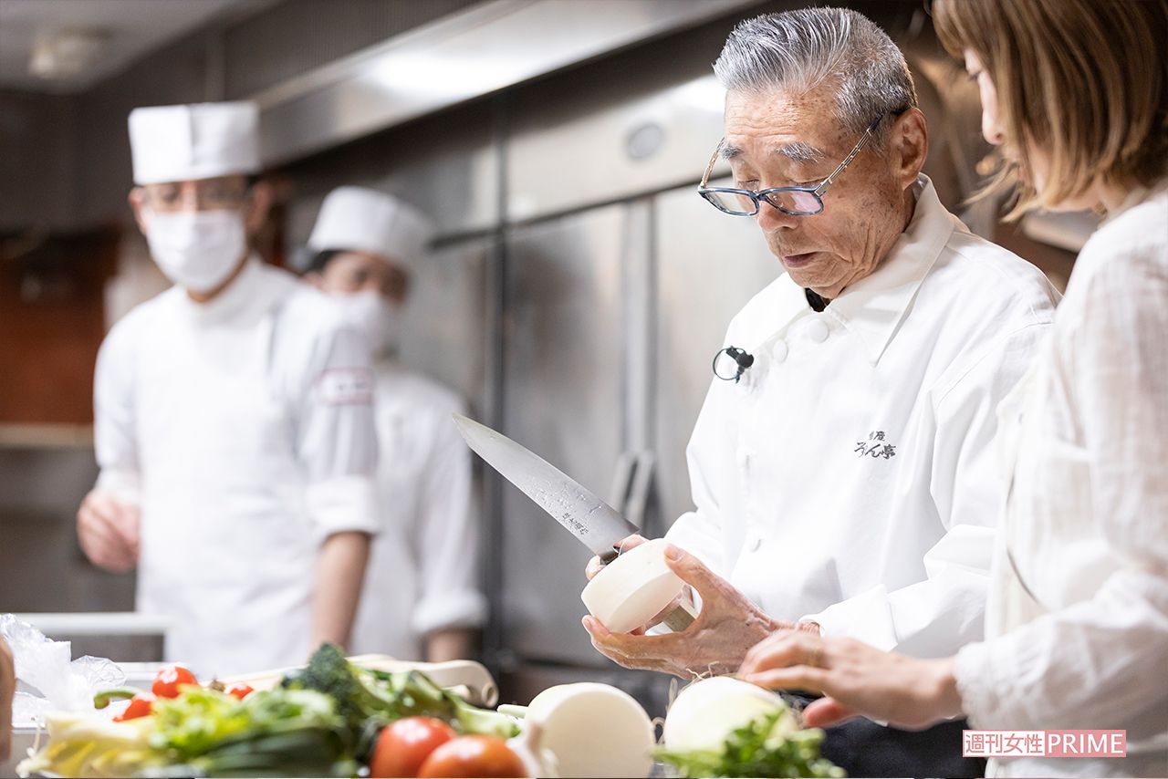 孫のなつきさんにかつら剥きの手本を見せる道場さん。その手元にお弟子さんたちの視線も集まる　撮影／齋藤周造