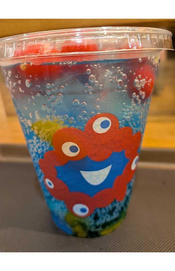 エスタシオンカフェにて販売されている『ミャクミャクフルーツソーダ』。青いソーダに真っ赤なチェリーが浮かぶ（Xより）