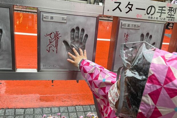 加トちゃんの「スターの手形」にそっと手を合わせる姪っ子