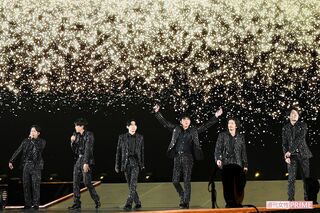 黒の衣装を纏い、華やかなステージで歌うV6のメンバー