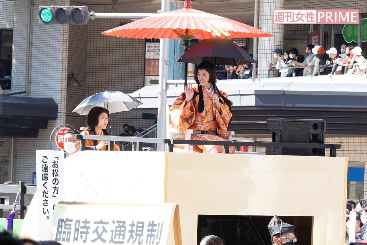 和傘に加え日傘をさして移動車に乗る栗山千明の周りには、撮影自粛を呼びかけるスタッフが