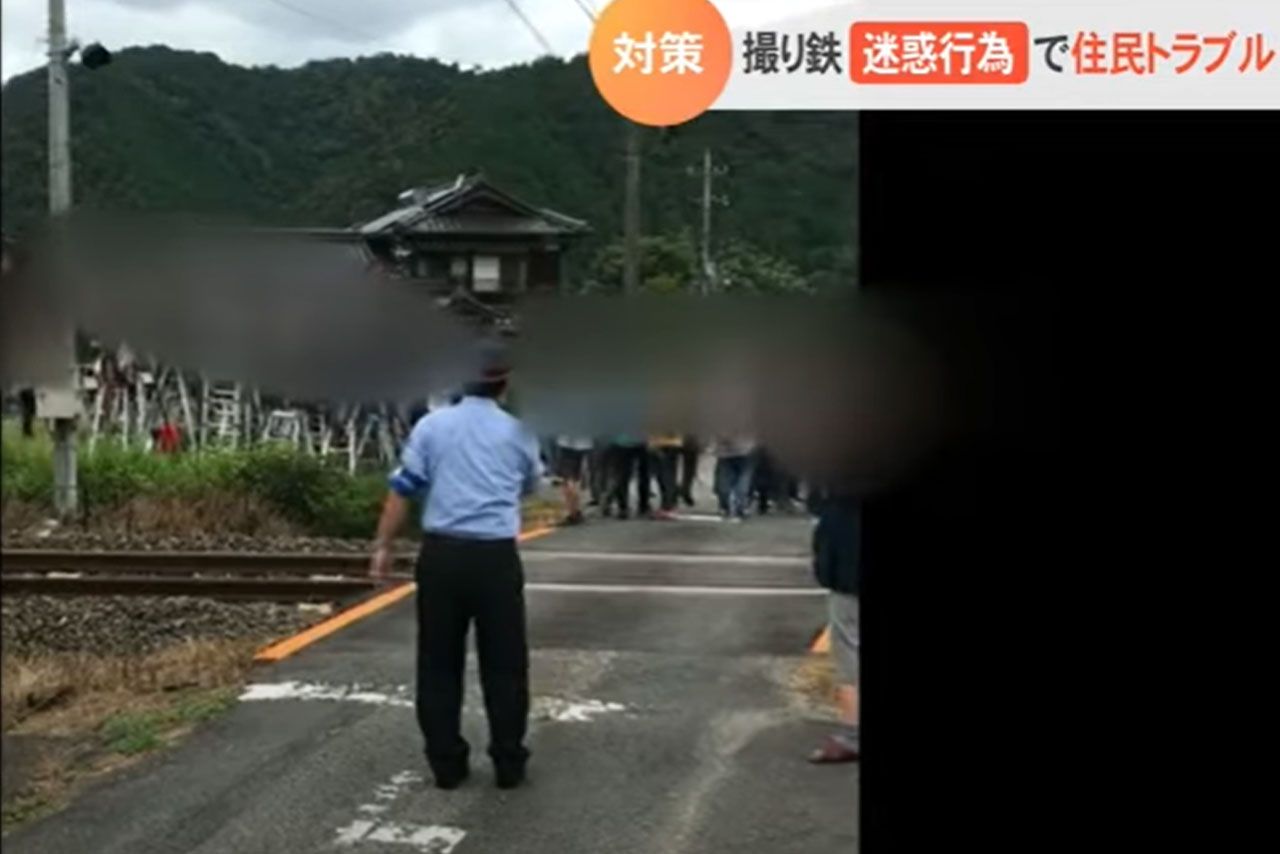 踏切付近の撮り鉄に拡声器を使って注意をする職員（山陰放送・テレポート山陰公式YouTubeより）