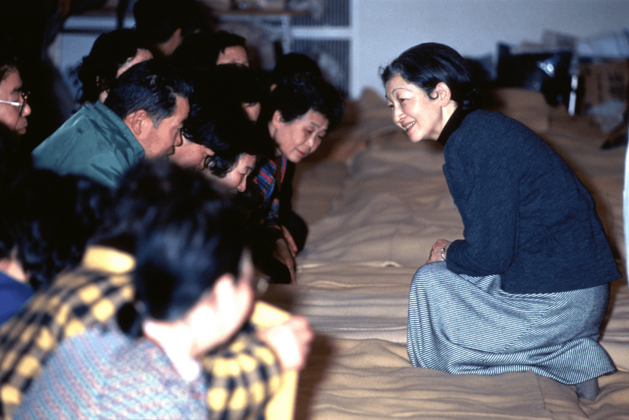 阪神・淡路大震災の避難所で膝をついて被災者を励まされた（'95年1月）