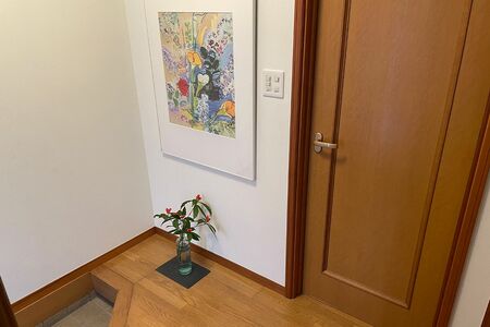 靴箱をなくしたスペースには大きめの絵と、床には季節の花を飾る。今はあまり使っていなかった廊下の収納棚を靴入れに使用