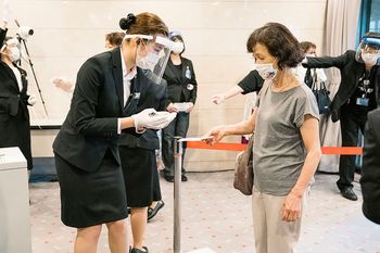 フェイスシールドをつけた係員が、チケットとマスク着用を確認