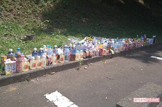 事件現場の駐車場には多くの飲み物などが供えられている