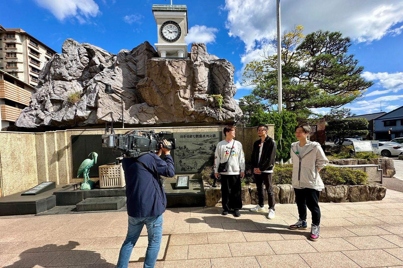 湯元の広場の時計台前にて。中央左から酒井さん、岩永洋昭さん、後上翔太さん