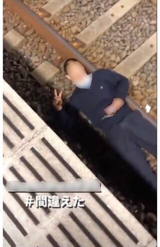 SNSで拡散されている、線路上で寝転ぶ若い男性。ピースサインでおどけるが…