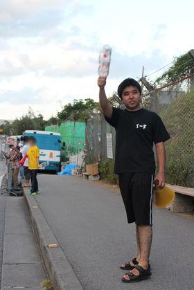 米軍基地の前に立ち、キャンドルを掲げ基地反対を訴える渡具知さん